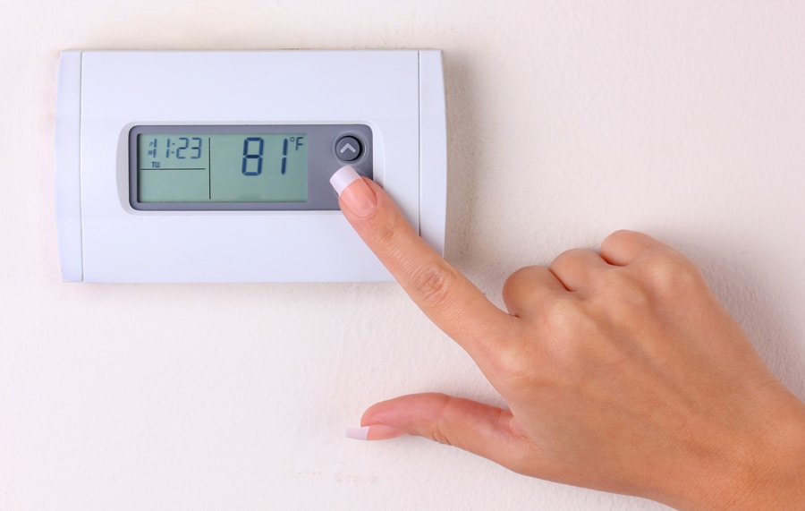 thermostat. woman's hand setting the room temperature on a modern programmable wall heater. closeup